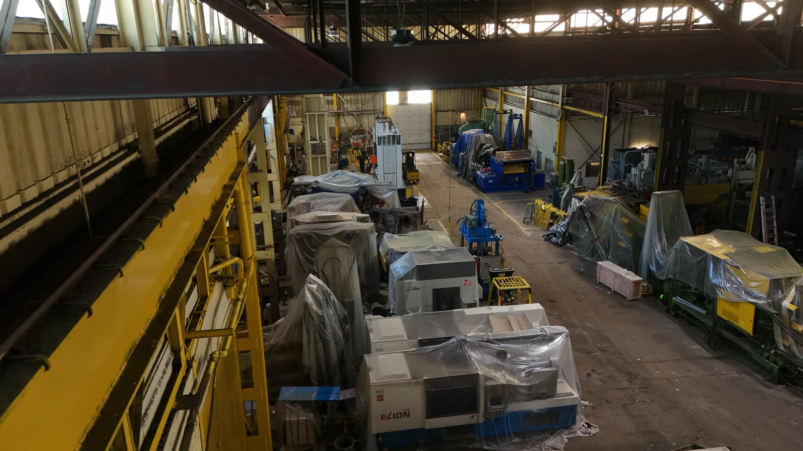 Covered CNC machines and industrial equipment stored on the actual warehouse floor