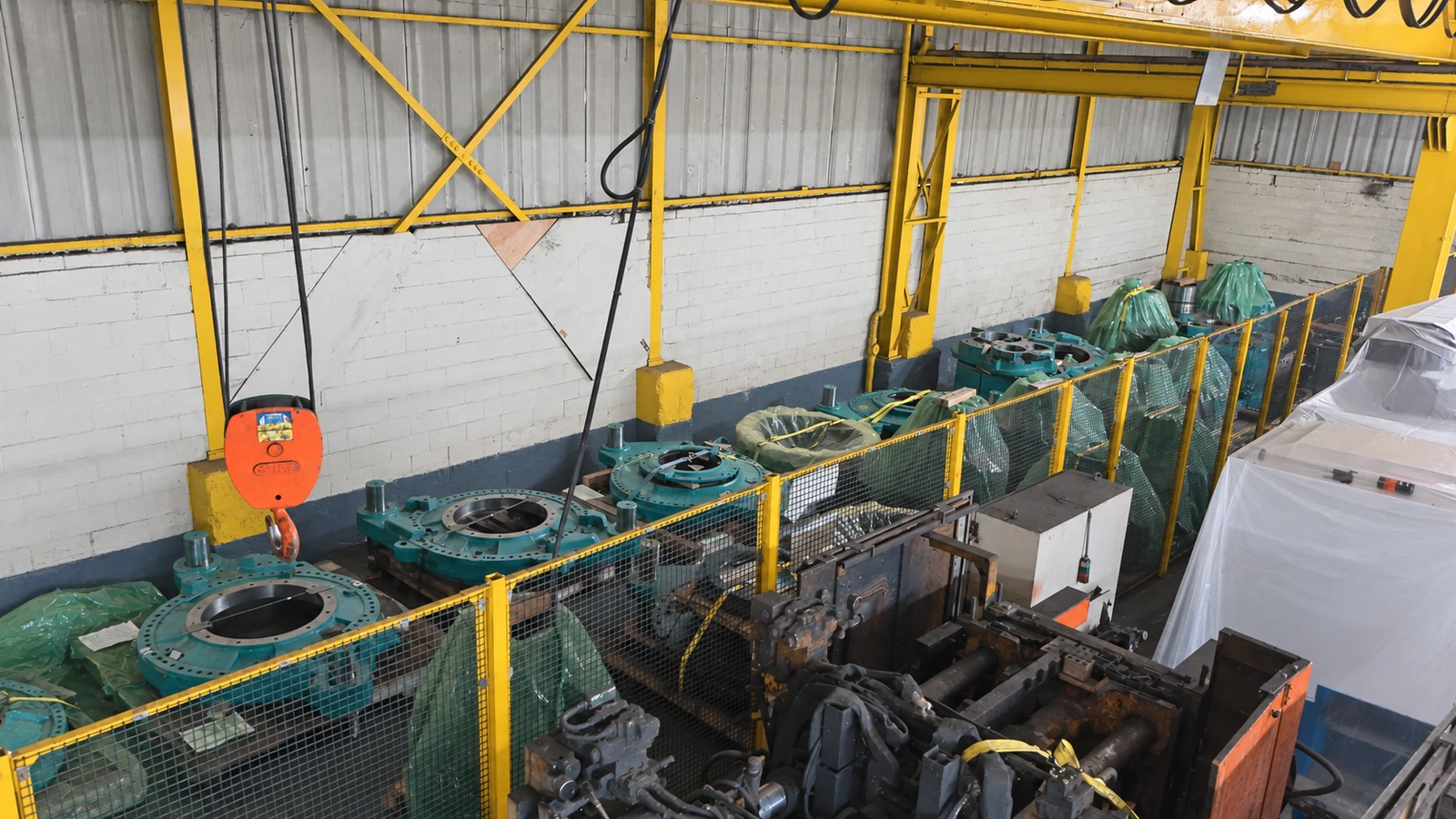 Industrial components in a fenced area within the shared warehouse.