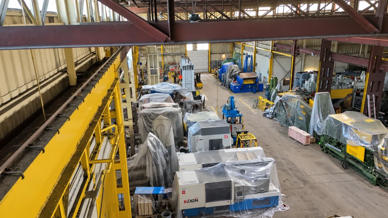 Covered CNC machines and industrial equipment arranged on the warehouse floor.