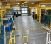 Blue warehouse racking beside a concrete aisle and industrial storage area.