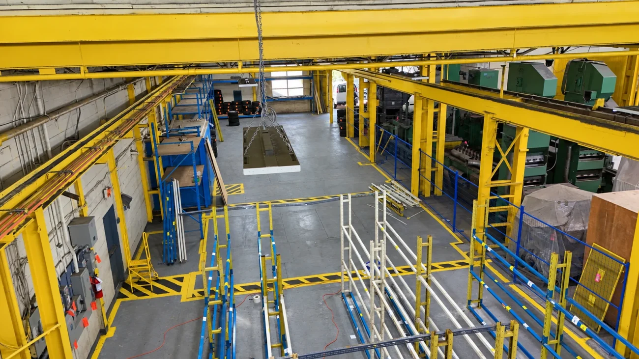 Industrial storage area with blue racks, yellow steel structure and stored equipment.