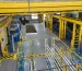 Industrial storage area with blue racks, yellow steel structure and stored equipment.